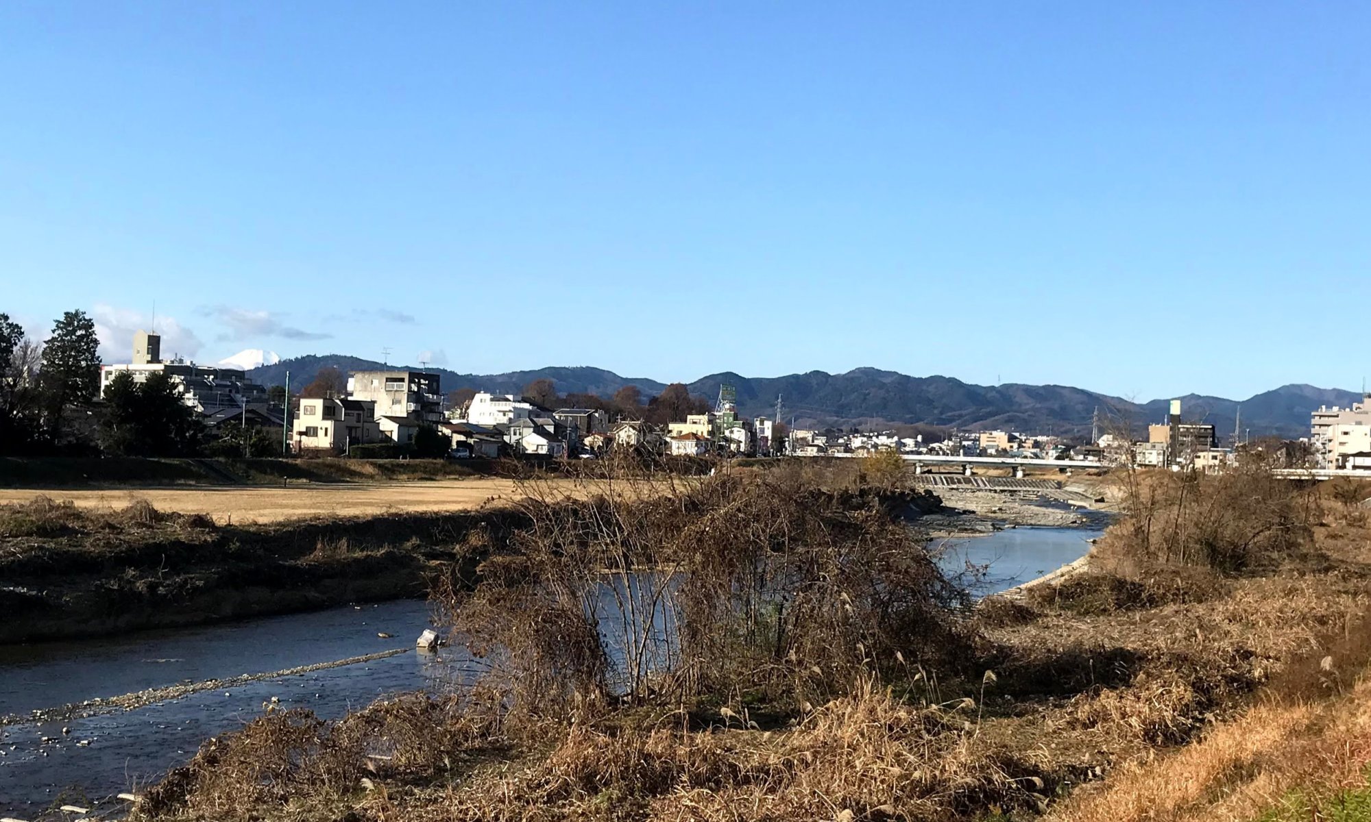 元朝の午前8時、光降り注ぐ浅川と遠くに富士山